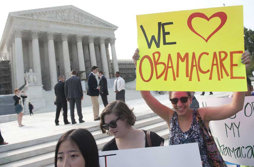 Protestor holding sign 'We love Obamacare' with others with Supreme Court in the background.