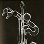 Tall, narrow, glass instrument with curved, cylindrical pipes and valves.