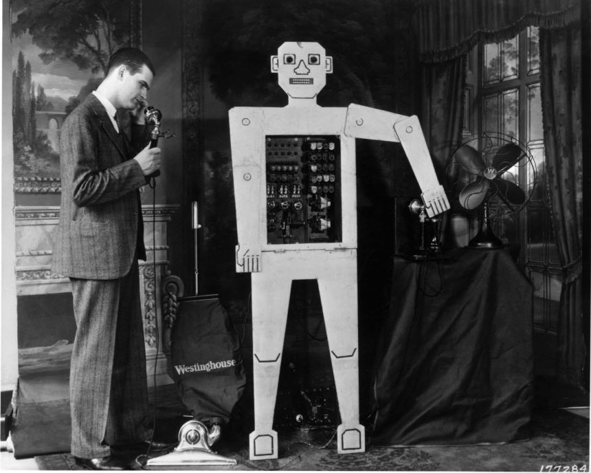 A man in suit looking at life-size mechanical man with electronic parts in its midsection