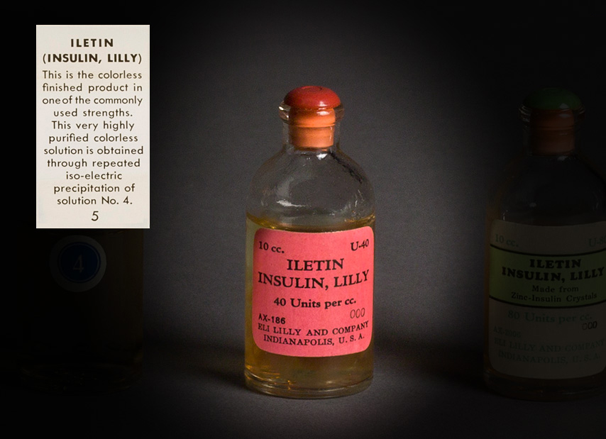 A clear glass bottle sealed with a pink label that reads  “10 cc. U-40, ILETIN INSULIN, LILLY, 40 units per cc. 000, AX-186, Eli Lilly and Company, Indianapolis, U.S.A.”