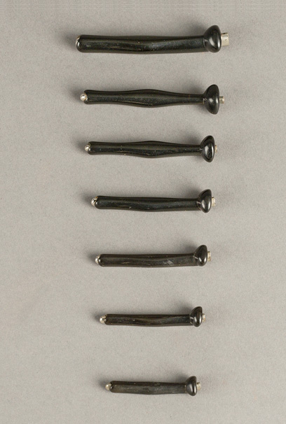 Row of seven hard rubber intubation tubes arranged by length.