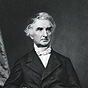 Half-length portrait of a man standing with the right arm over back of a chair