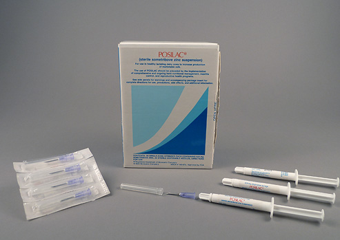 Blue and white box with three white syringes, a needle, and a package of four needles displayed around the box.