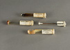 Four glass test tubes with paper labels and cotton plugs. Dried culture media is in three tubes and a metal cotton swab is in the fourth.