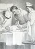 A man in gown gives an injection to a small child laying on a table.  Two women in nursing gowns and caps attend to the child at its head and side.