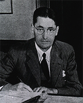 Black-and-white photo of Florey at a desk up which there are some papers.