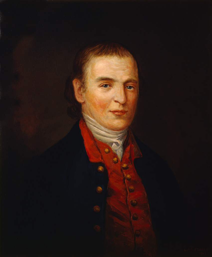 Dr. James Craik wearing white shirt, red vest, blue jacket looking at the viewer.