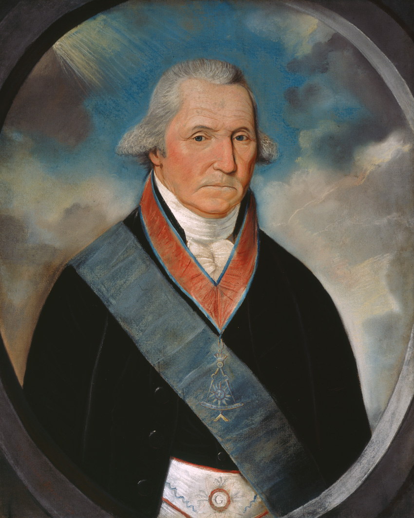 Halo of blue sky behind his gray hair, wearing a blue sash across his chest on top of his jacket. 