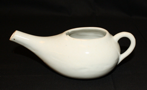 Color photograph of a white ceramic pot with a spout and a handle.