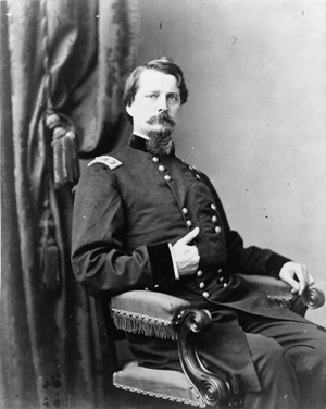 Black and white photograph of a Union Major General Winfield S. Hancock in uniform, seated, right pose with his right hand tucked into his jacket.