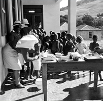African children gather outside to receive vaccinations from an African nurse.