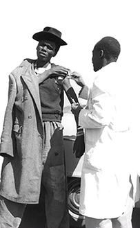 An African man receives a vaccination in his arm from an African doctor.