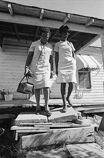 Two African American nurses walking out of a patient’s home.