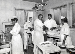 Three surgeons and two nurses wearing medical uniforms performing surgery on a patient in an operating room.