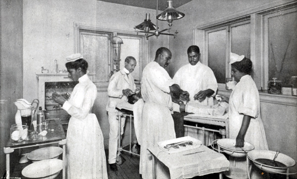 Three surgeons and two nurses wearing medical uniforms performing surgery on a patient in an operating room.