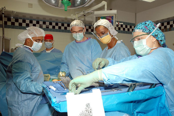 Five members of a surgical team in an operating room with surgical instruments in the foreground. 