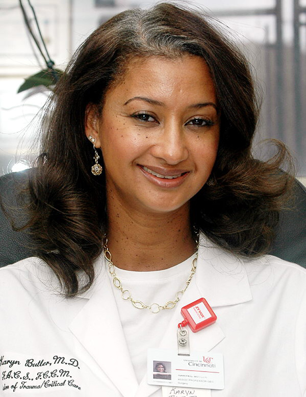 A woman smiling in white medical coat.