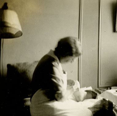 Female nurse doing a male patient’s dressing while sitting next to a table with medical supplies.