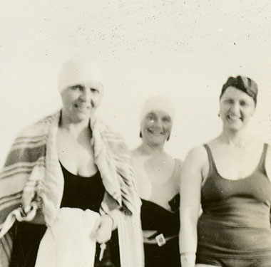 Posed group of seven women in one-piece swimsuits and bathing caps at Jones Beach.