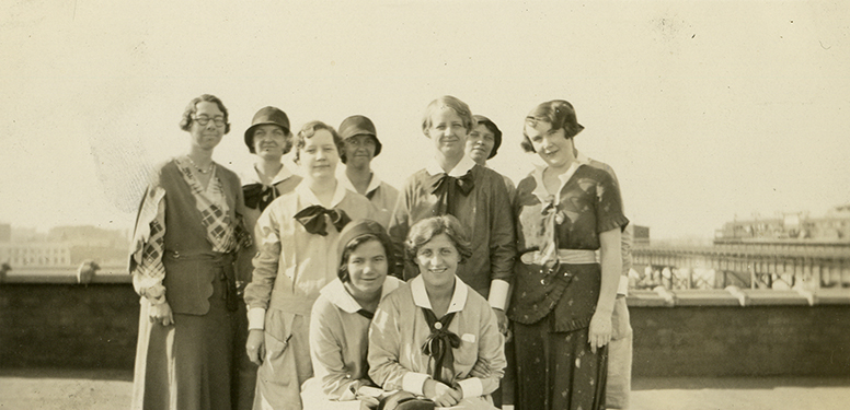 10 White females, 8 in nurse uniforms with cuffs and collars, neck ties, and 2 in dress suits.