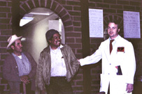 A Hispanic male in a farmer’s hat, an African American male, and a White male doctor in a lab coat.
