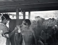 A boy being sprayed with pesticide by a uniformed woman.
