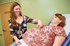 A smiling White woman examines a pregnant White woman on an examination table.