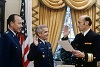 Smiling White man in uniform takes an oath of office from other White man in uniform.