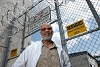 Smiling African American man in a lab coat stands in front of a prison entrance.