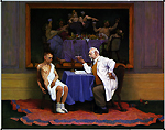 Doctor speaking to half naked patient with painting of a feast of wine in the background.