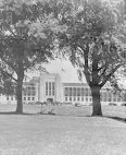 The front exterior of the U.S. Public Health Service Hospital in Lexington, Kentucky. The hospital can be seen in the background between two large trees.