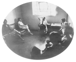 A group rehabilition program of treatment at the Lexington Hospital. A group of people is on couches around the room while a doctor in a white lab coat sits at the far end of the room in a chair.