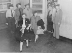 Passengers from London entering the quarantine room at LaGuardia Airport in New York City with four inspection officers standing near the door.