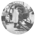 Men wearing white gowns load bundles of clothing into large sterilizers.