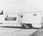 Exterior view of the mobile examination center. A sign, National Health and Nutrition Examination Survey, hangs on front of the center.