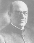 Head and shoulders, right pose, full face of Joseph J. Kinyoun wearing glasses.