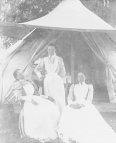 Three nurses outside a tent at the temporary yellow fever hospital in Franklin, Louisiana. Two of the nurses are seated while the third nurse stands between them.