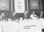 Vice President George Bush sits at a table addressing the AIDS Executive Committee. Seated at a table are doctors Raub, Wyngaarden, Vice President Bush and Dr. Anthony Fauci.