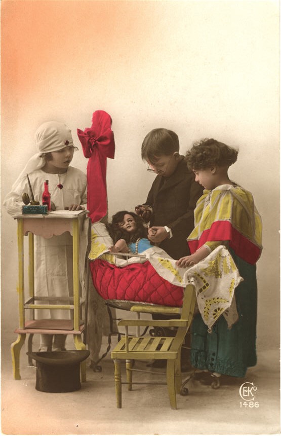 White children dressed as a nurse, doctor, and mother. All stand over a doll in a crib.