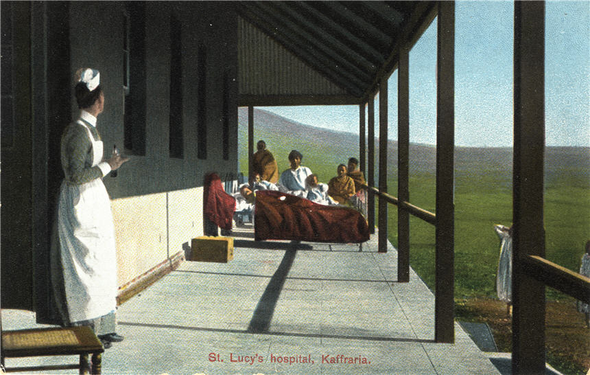 A White female nurse in foreground looking at patients gathered around three cots on a porch.
