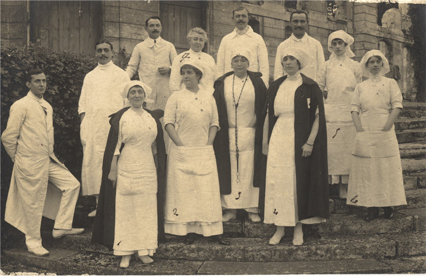 5 White men and 7 White women in medical uniforms, standing on the steps of a building.