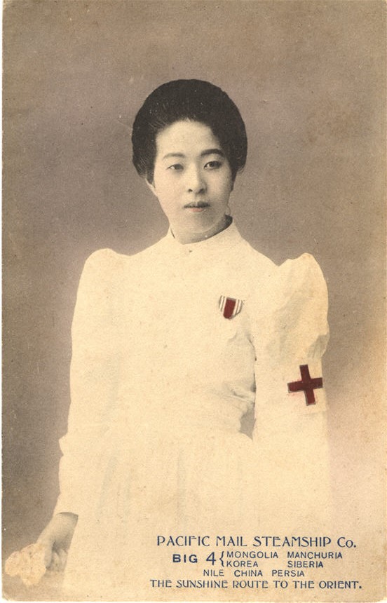 An Asian female nurse in white, wearing war medal, looking slightly off to the right.