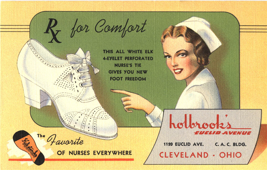 A White female nurse in white smiles at viewer, and points towards a white heeled shoe.