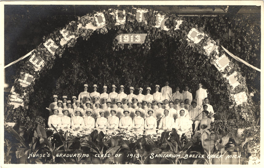 Large group of White male and female nurses in white sitting and standing for a group photo.
