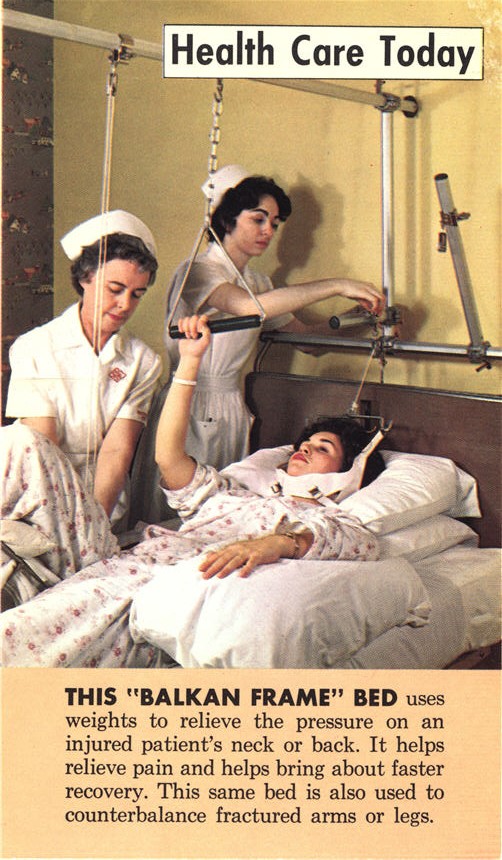 Two White female nurses adjust a support system that surrounds a White woman patient in a bed.