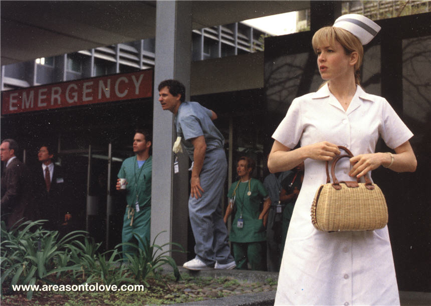 A White female nurse in white, looking off to the left along with group of hospital staff.