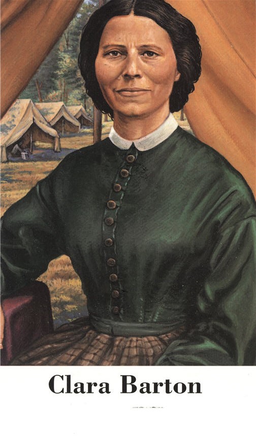 A White female nurse in green dress, sitting in tent looking at the viewer.
