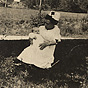 An African American female little person nurse holding a White infant and sitting outside.