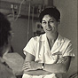 A White female nurse in scrubs, smiling and addressing a patient out of the image.