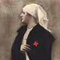 A White female nurse in white wearing blue overcoat, looking to the left.